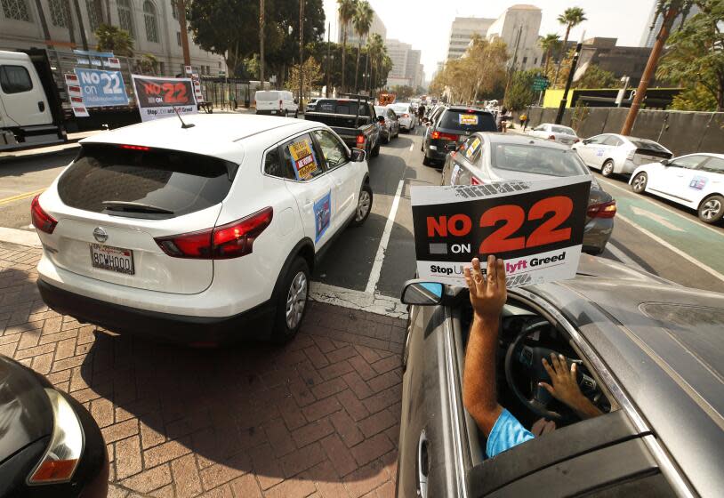 LOS ANGELES, CA - OCTOBER 08: Rideshare driver Jorge Vargas raises his No on 22" sign in support as app based gig workers held a driving demonstration with 60-70 vehicles blocking Spring Street in front of Los Angeles City Hall urging voters to vote no on Proposition 22, a November ballot measure that would classify app-based drivers as independent contractors and not employees or agents, providing them with an exemption from California's AB 5. The action is part of a call for stronger workers' rights organized by the Mobile Workers Alliance with 19,000 drivers in Southern California and over 40,000 in all of California. Los Angeles on Thursday, Oct. 8, 2020 in Los Angeles, CA. (Al Seib / Los Angeles Times