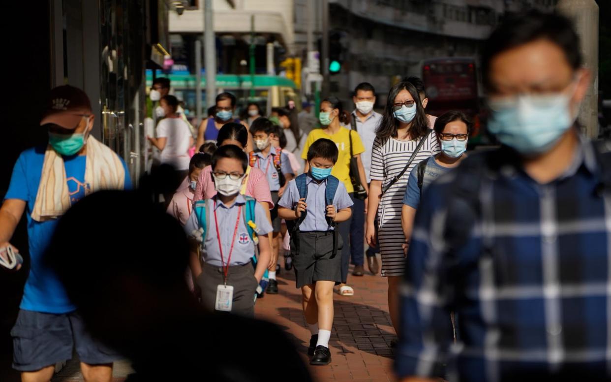 A group of young Hong Kong children in uniform walk to school with masks on - Roy Liu/Bloomberg 