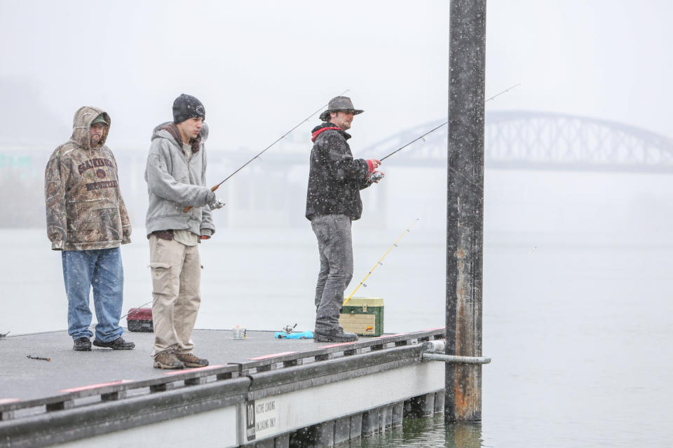 From right, Greg Holcomb, 33, John Carpenter, 25, and Dave Blackhurst, 34, all of Charleston, fish in the Kanawha River at Haddad Riverfront Park during a steady snow shower, Sunday, March 16, 2014, in Charleston, W.Va. (AP Photo/Charleston Daily Mail, Marcus Constantino)