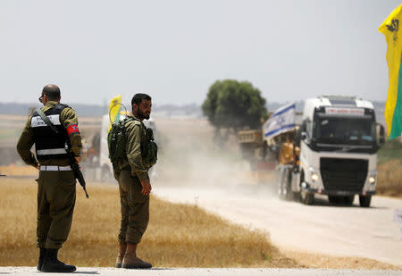 Israeli solders stand as a transporter carrying a tank drives by, on the Israeli side of the border between Israel and Gaza, near kibbutz Mefalsim, May 30, 2018. REUTERS/Amir Cohen