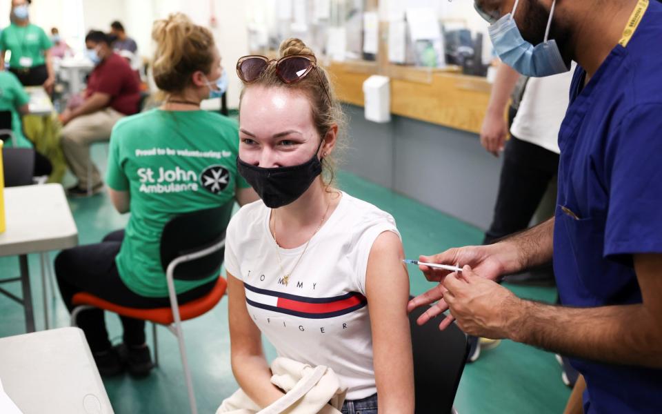 A young person receives a dose of the Pfizer BioNTech vaccine at a vaccination centre in Harrow - REUTERS