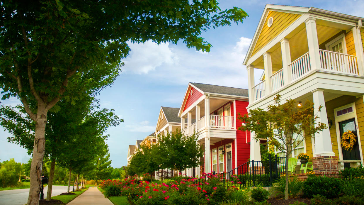 Row of colorful garden homes with two stories and white pillars in suburban neighborhood of Fayetteville, Arkansas.