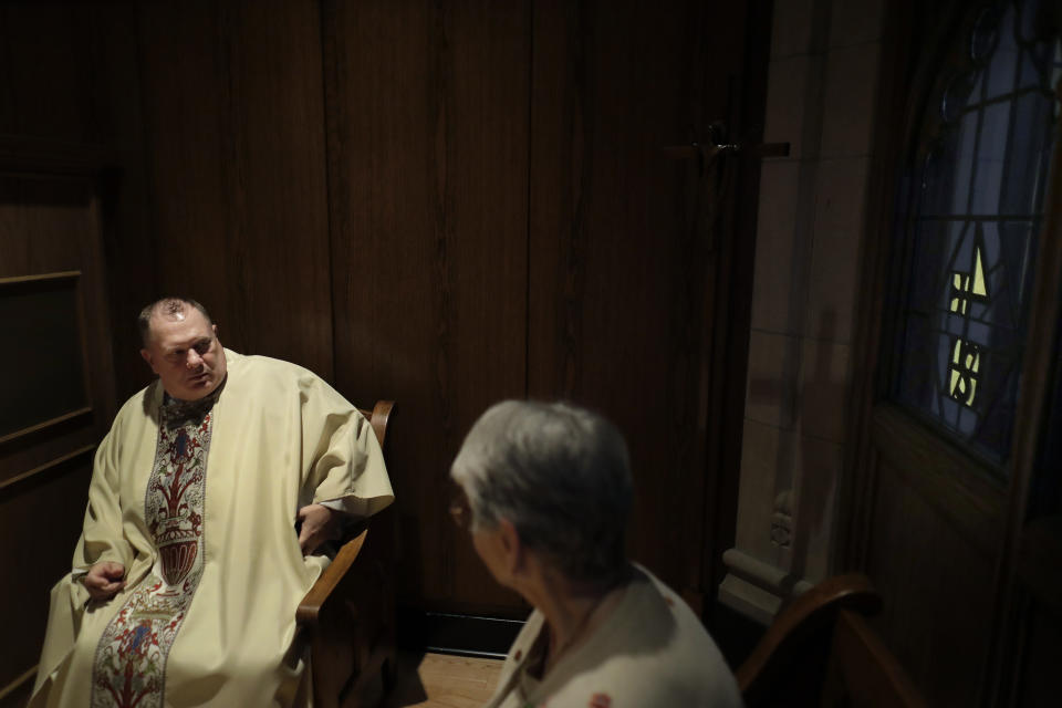 In this Thursday, Oct. 31, 2019 photo, Rev. Mark Stelzer, a professor and chaplain at College of Our Lady of the Elms, speaks with sacristan Marlene Czepiel, right, in the sacristy before offering Mass in the school's chapel, in Chicopee, Mass. Stelzer is also administrator of St. Jerome's Parish, in Holyoke, Mass., where he lives alone in a rectory while serving as spiritual leader to the 500 families in the Catholic parish. (AP Photo/Steven Senne)