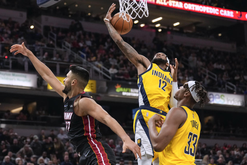 Indiana Pacers forward Oshae Brissett (12) pulls in a rebound next to Miami Heat center Omer Yurtseven (77) during the first half of an NBA basketball game in Indianapolis, Friday, Dec. 3, 2021. (AP Photo/AJ Mast)