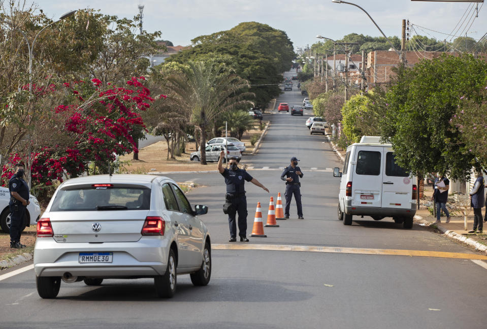 Police check commuters for symptoms of COVID-19 at the entrance of Serrana, Sao Paulo state, Brazil, Friday, May 28, 2021. Brazil's Butantan Institute has finished a mass vaccination of the city's entire adult population with doses of Sinovac, to test the new coronavirus' behavior in response to the vaccine. (AP Photo/Andre Penner)