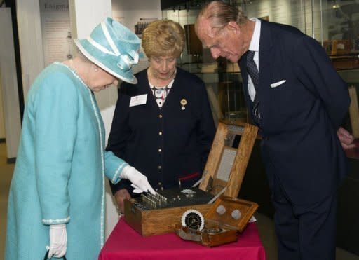 Queen Elizabeth II (L) and husband Prince Philip, with wartime operator Ruth Bourne (C), presses a button on the Enigma codebreaking machine during a visit to Bletchley Park, near London, in July 2011. Bletchley Park housed the British decoding effort during World War II