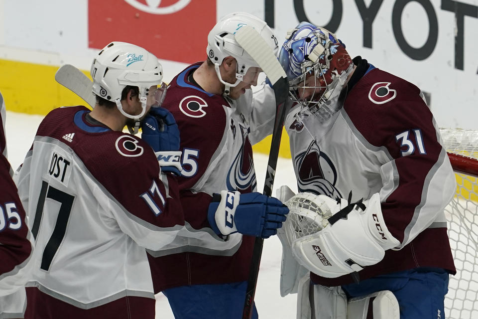 Colorado Avalanche center Tyson Jost, left, celebrates with right wing Logan O'Connor and goaltender Philipp Grubauer, right, after the Avalanche defeated the San Jose Sharks in an NHL hockey game in San Jose, Calif., Wednesday, March 3, 2021. (AP Photo/Jeff Chiu)