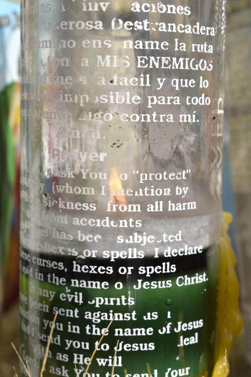 A Christian prayer for protection is printed on a lit candle at the memorial for farm workers who were killed in a crash in Madera.