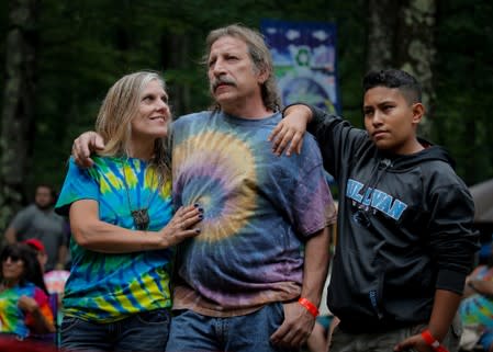 People listen to a band during a celebration of the 50th anniversary of the Woodstock Festival on Max Yasgur's original homestead in Bethel, New York