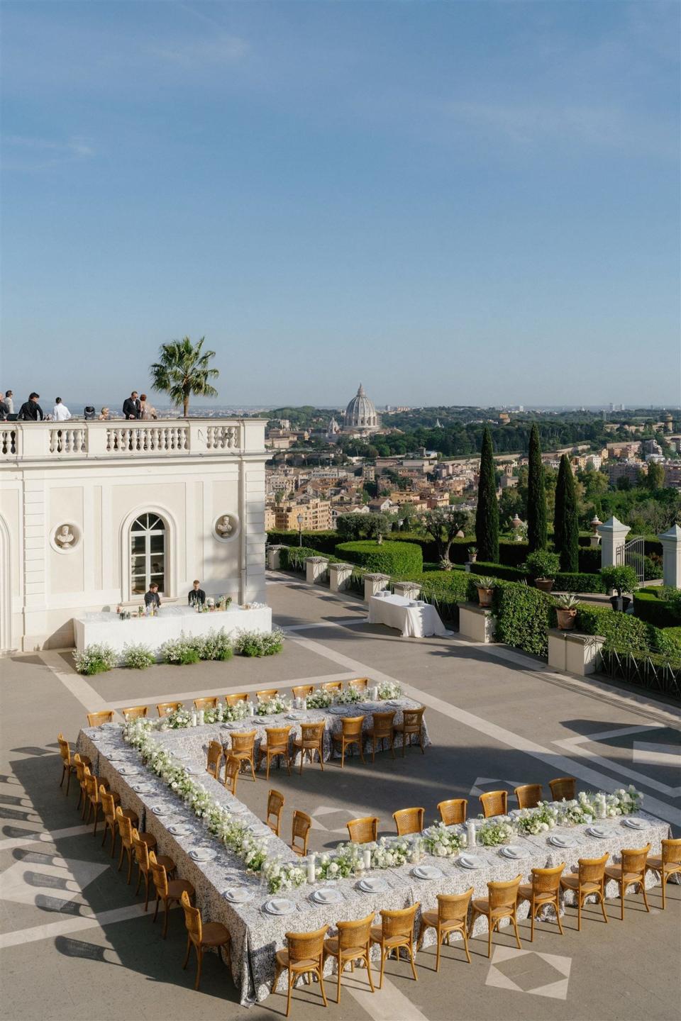 An outdoor wedding with a massive u-shaped table and bar.