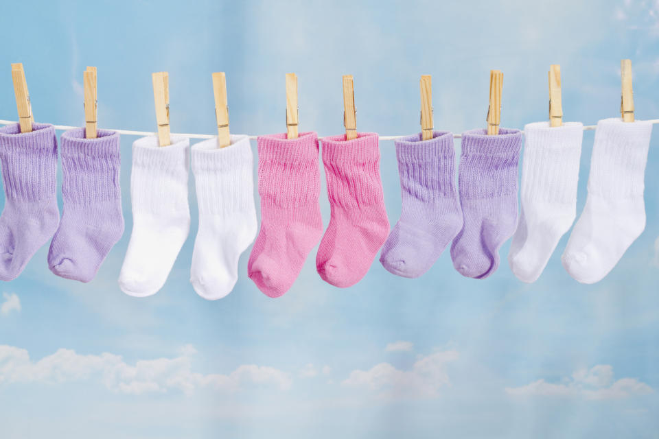 Assorted baby socks hanging on a clothesline with a sky background.