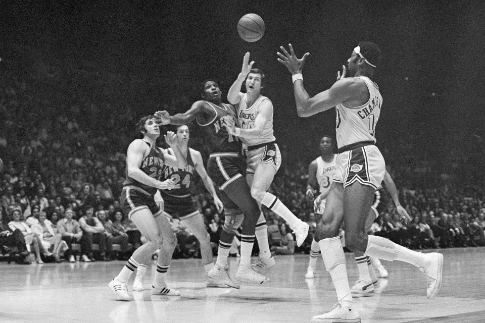 FILE -FILE - Los Angeles Lakers Jerry West, right, passes the ball to Wilt Chamberlain Monday night, April 28, 1970, during a game with the New York Knickerbockers at New York's Madison Square Garden. Covering West are Knicks Willis Reed (19), left, and Walt Frazier (10), center. Jerry West, who was selected to the Basketball Hall of Fame three times in a storied career as a player and executive and whose silhouette is considered to be the basis of the NBA logo, died Wednesday morning, June 12, 2024, the Los Angeles Clippers announced. He was 86.(AP Photo, File)