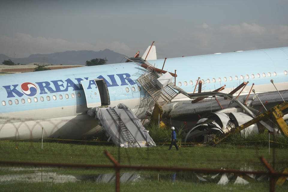 A man walks beside a damaged Korean Air plane after it overshot the runway at the Mactan-Cebu International Airport in Cebu, central Philippines early Monday Oct. 24, 2022. The Korean Air plane overshot the runway while landing in bad weather in the central Philippines late Sunday, but authorities said all 173 people on board were safe. (AP Photo/Juan Carlo De Vela)