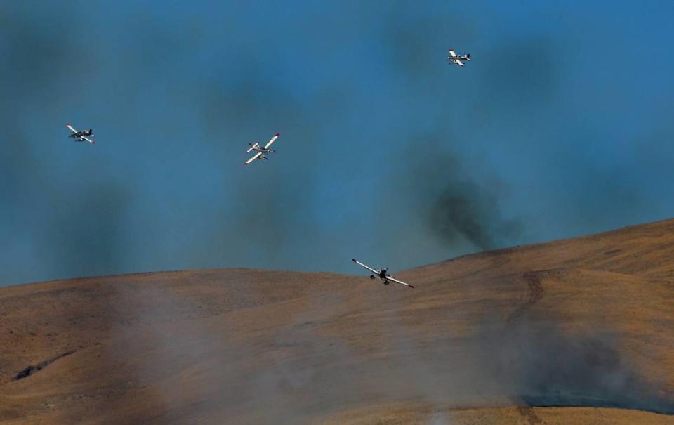 A group of fire fighting aircraft line up in the sky preparing to drop their loads water at a two-alarm wildfire that forced people from homes Monday afternoon just north of Benton City. There were no immediate details on the size or cause of the blaze.