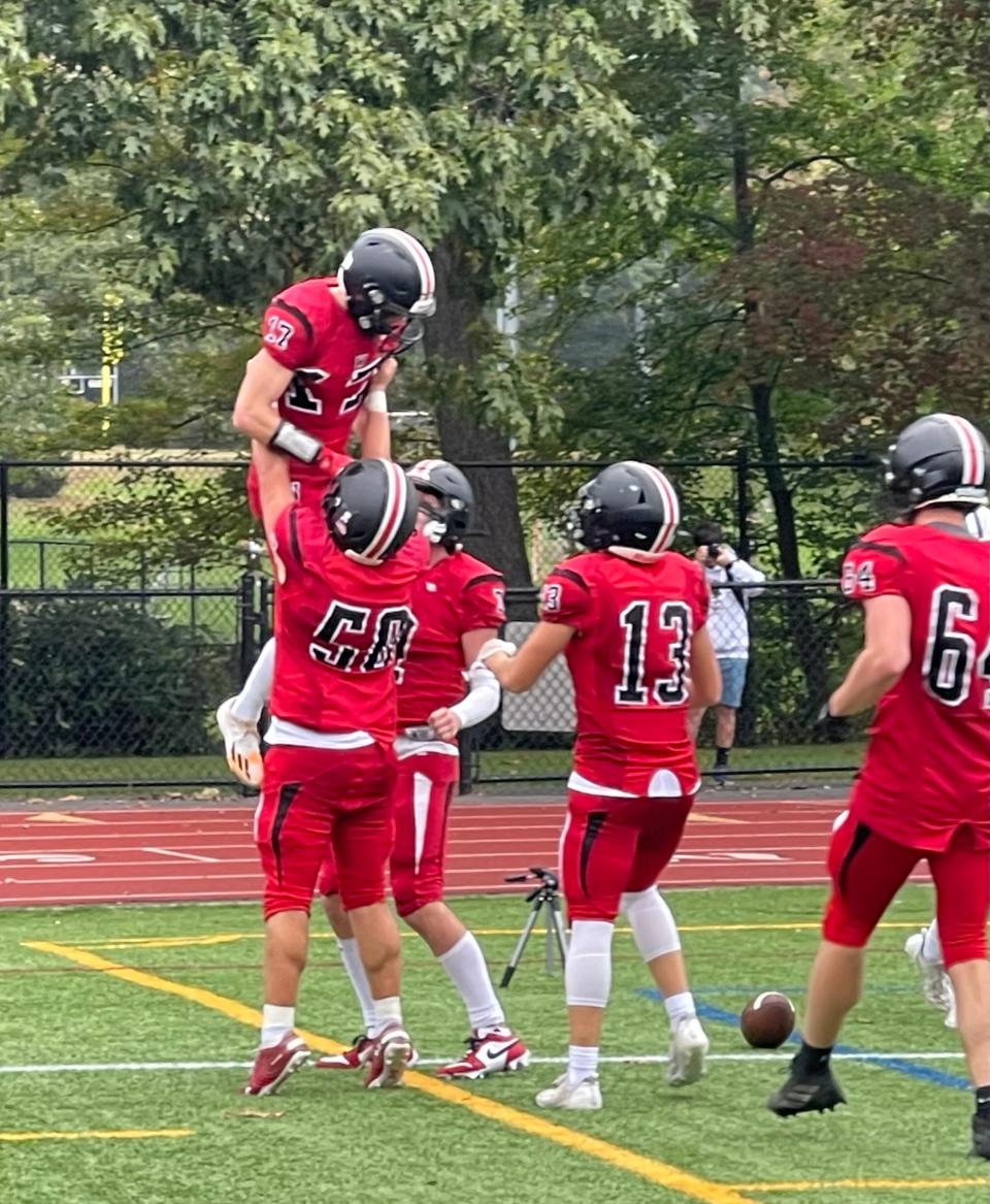 Wellesley senior captain Robby Broggi is lifted up after scoring a touchdown against Framingham on Saturday, Oct. 7, 2023.