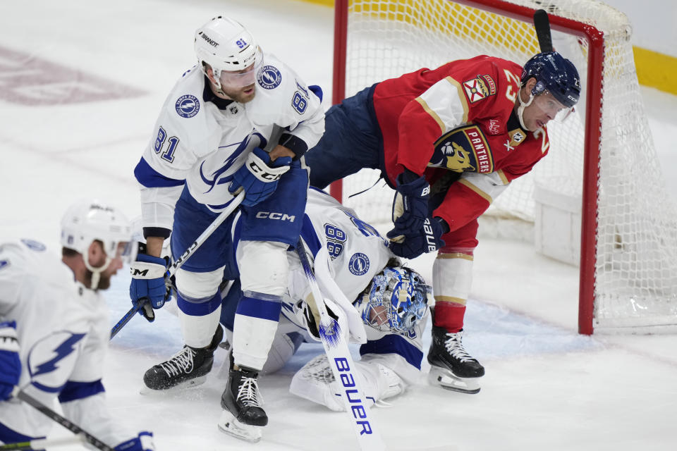 Florida Panthers center Carter Verhaeghe (23) skates into Tampa Bay Lightning goaltender Andrei Vasilevskiy (88) as defenseman Erik Cernak (81) looks on during the second period of Game 2 of the first-round of an NHL Stanley Cup Playoff series, Tuesday, April 23, 2024, in Sunrise, Fla. Verhaeghe was charged with goaltender interference. (AP Photo/Wilfredo Lee)