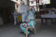 A health worker takes a swab test of a woman during a free medical checkup in Dharavi, one of Asia's biggest slums, in Mumbai, India, Friday, June 26, 2020. India is the fourth hardest-hit country by the pandemic in the world after the U.S., Russia and Brazil. (AP Photo/Rafiq Maqbool)