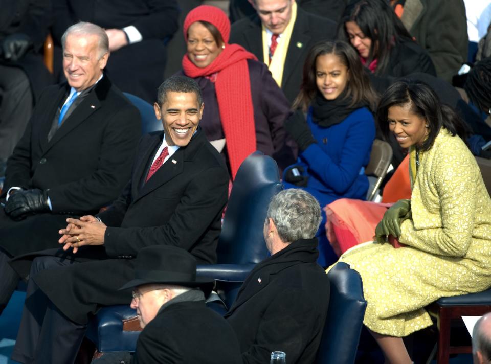 President Barack Obama smiles at George W. Bush as they listen to the inauguration ceremony at the U.S. Capitol in Washington, Tuesday, Jan. 20, 2009. Vice President Joe Biden sits left of Obama and his family, including wife Michelle, far right, and daughters Malia and Sasha (hidden behind Michelle).