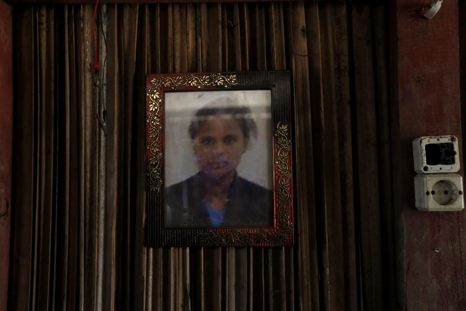 In this Oct. 21, 2018, photo, a framed photo of Adelina Sau hangs on the wall of her family's home in Abi village in West Timor, Indonesia. Adelina had been working as a maid for a Malaysian family when a local lawmaker's office received a tip from neighbors who suspected she was being abused. Following her death, an autopsy determined she died of septicemia and cited possible abuse and neglect. (AP Photo/Tatan Syuflana)