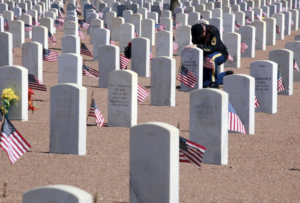 A soldier sits in front of a grave during Memorial Day celebrations at Fort Bliss in El Paso, Texas, on May 25, 2015.