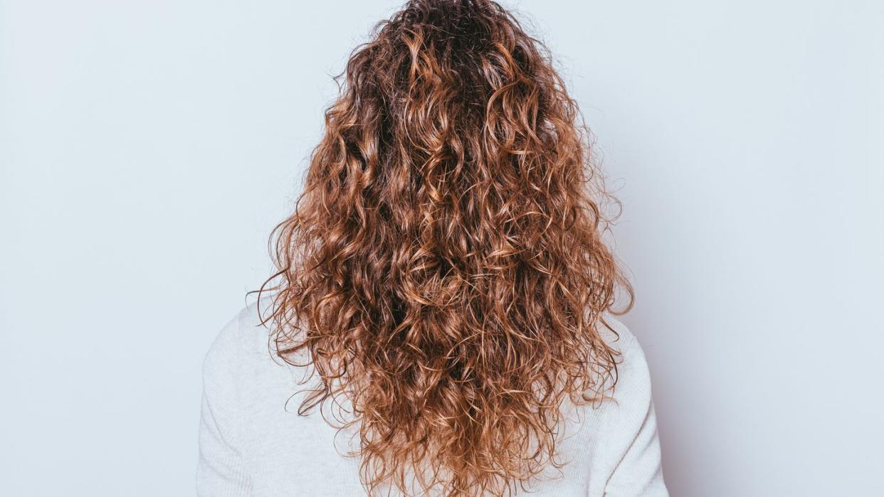 rear view woman's head with beautiful long naturally curly hair