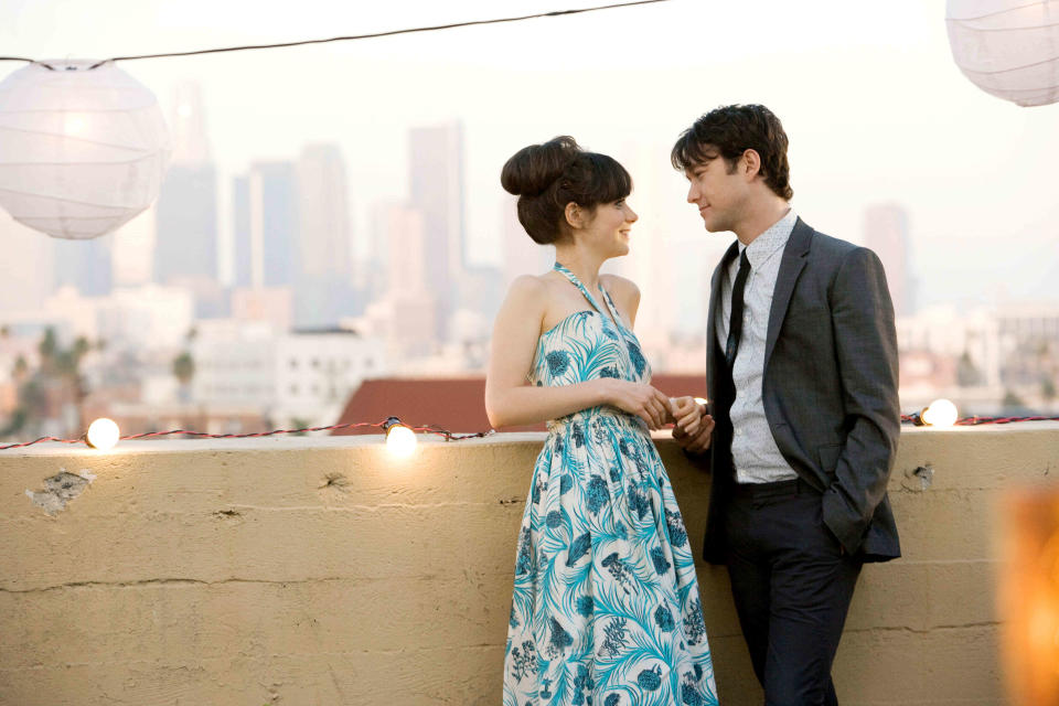 Two characters from the movie "500 Days of Summer" sharing a moment on a rooftop with city skyline in the background