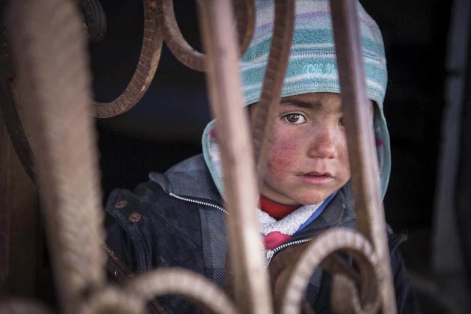 In this picture taken, Feb. 16, 2017, a child looks out from an abandoned petrol station where he and his family now live. The petrol station, badly damaged by war, is now the home of five families who have returned to Tel Abiad district, Raqqa Governorate, Syria, after fleeing from ISIS two years earlier only to find their homes destroyed. A new report by Save the Children says Syrian children are showing symptoms of ‘toxic stress’ from war exposure, and attempting self-harm and suicide. (Photo Courtesy: Jonathan Hyams, Save the Children via AP)