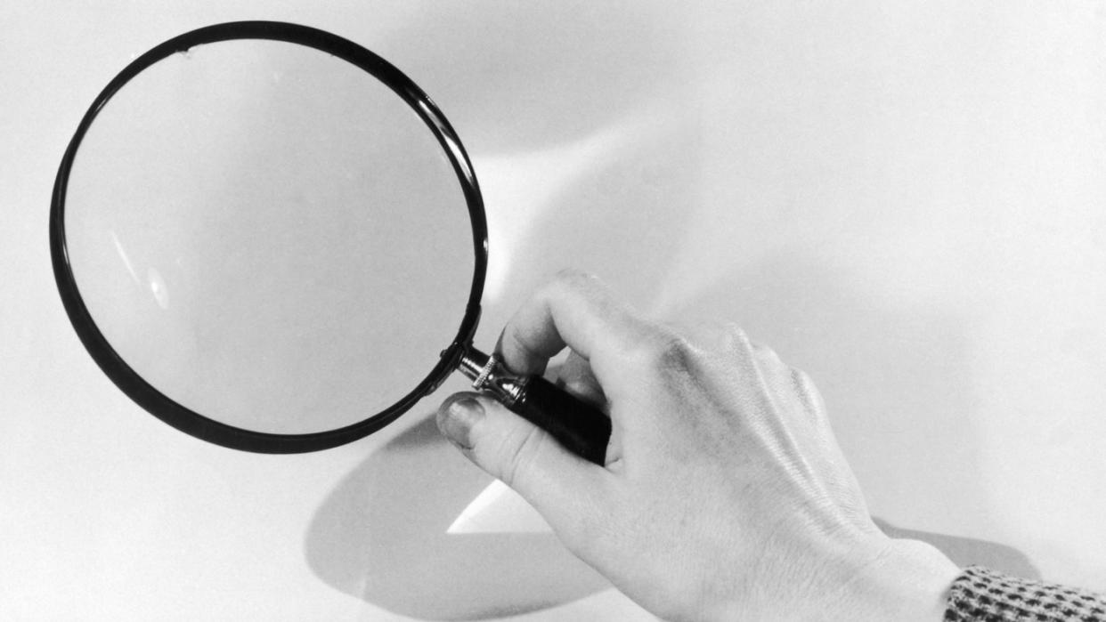   A hand holding a magnifying glass. 