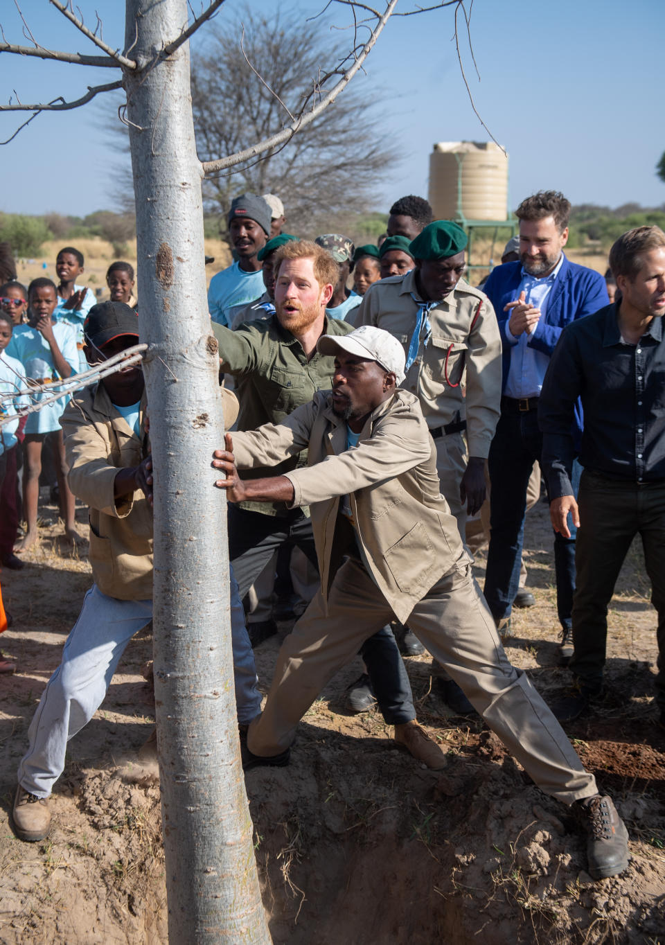 The Duke of Sussex (centre) helps plant a baobab tree during a tree planting event with local children, at the Chobe National Park, Botswana.