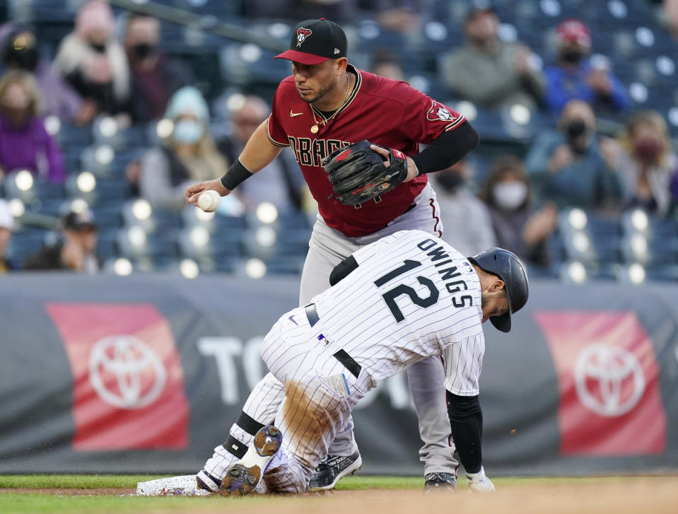 Colorado Rockies' Chris Owings, front, slides safely into third base with an RBI triple as Arizona Diamondbacks third baseman Asdrubal Cabrera fields the throw during the first inning of a baseball game Wednesday, April 7, 2021, in Denver. (AP Photo/David Zalubowski)