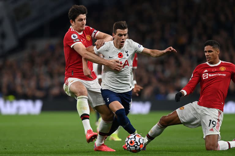 Tottenham Hotspur's Argentinian midfielder Giovani Lo Celso (C) is fouled by Manchester United's English defender Harry Maguire (L) just outside the penalty area during the English Premier League football match between Tottenham Hotspur and Manchester United at Tottenham Hotspur Stadium in London, on October 30, 2021. (Photo by Glyn KIRK / AFP) / RESTRICTED TO EDITORIAL USE. No use with unauthorized audio, video, data, fixture lists, club/league logos or 'live' services. Online in-match use limited to 120 images. An additional 40 images may be used in extra time. No video emulation. Social media in-match use limited to 120 images. An additional 40 images may be used in extra time. No use in betting publications, games or single club/league/player publications. /