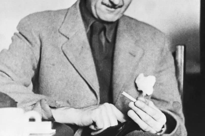 Black and white photo of George Orwell looking down at a cigarette in his hand