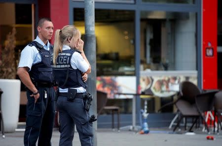 Police stand outside where a 21-year-old Syrian refugee killed a woman with a machete and injured two other people in the city of Reutlingen, Germany July 24, 2016. REUTERS/Vincent Kessler