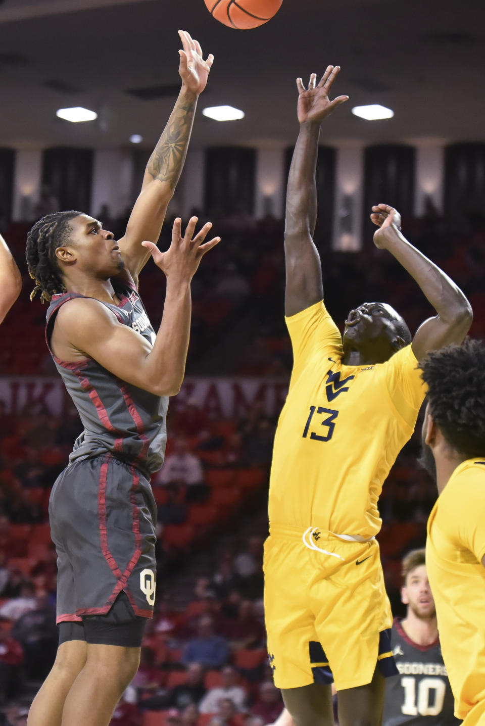 Oklahoma guard Javian McCollum, left, shoots over West Virginia forward Akok Akok during the first half of an NCAA college basketball game Wednesday, Jan. 17, 2024, in Norman, Okla. (AP Photo/Kyle Phillips)