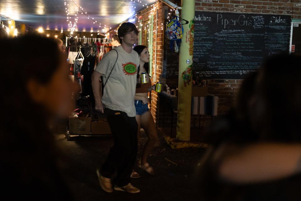 Two How Bazar A La Carte night market attendees walk with twisted teas in downtown Gainesville, Florida on Oct. 14, 2023.