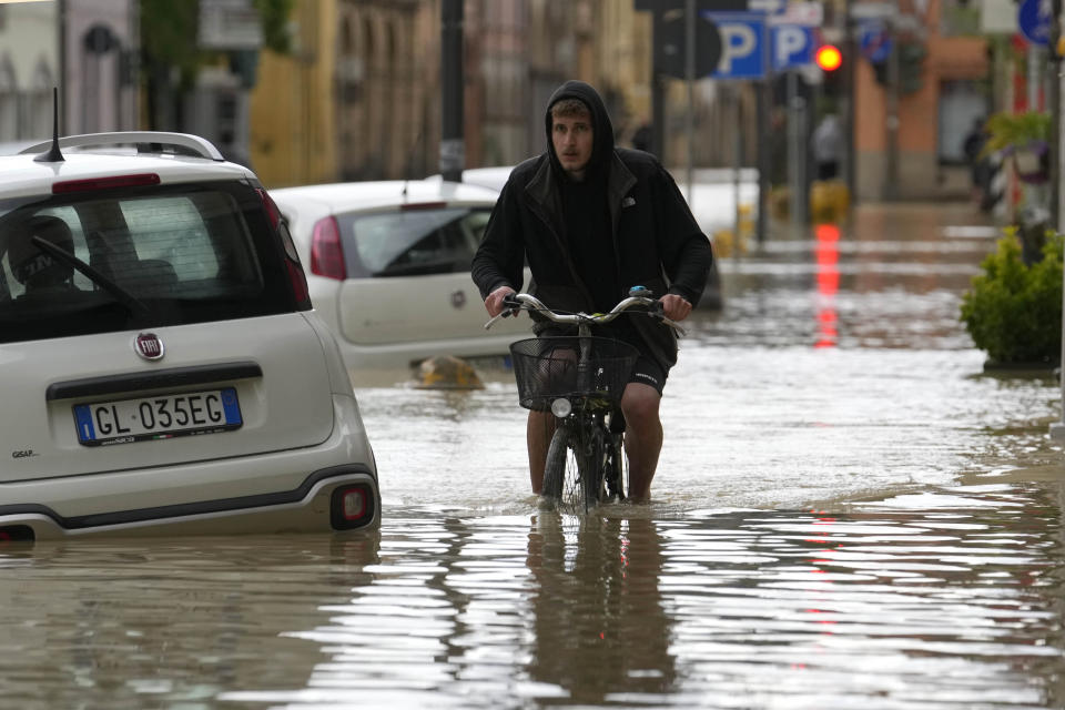 A man pedals in a flooded street in the village of Castel Bolognese, Italy, Wednesday, May 17, 2023. Exceptional rains Wednesday in a drought-struck region of northern Italy swelled rivers over their banks, killing at least eight people, forcing the evacuation of thousands and prompting officials to warn that Italy needs a national plan to combat climate change-induced flooding. (AP Photo/Luca Bruno)