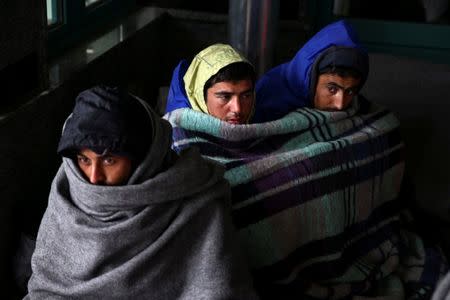 Refugees and migrants try to warm themselves as they take a break at a petrol station before abandoning their trek to the Hungarian border, in the town of Indjija, Serbia October 5, 2016. REUTERS/Marko Djurica