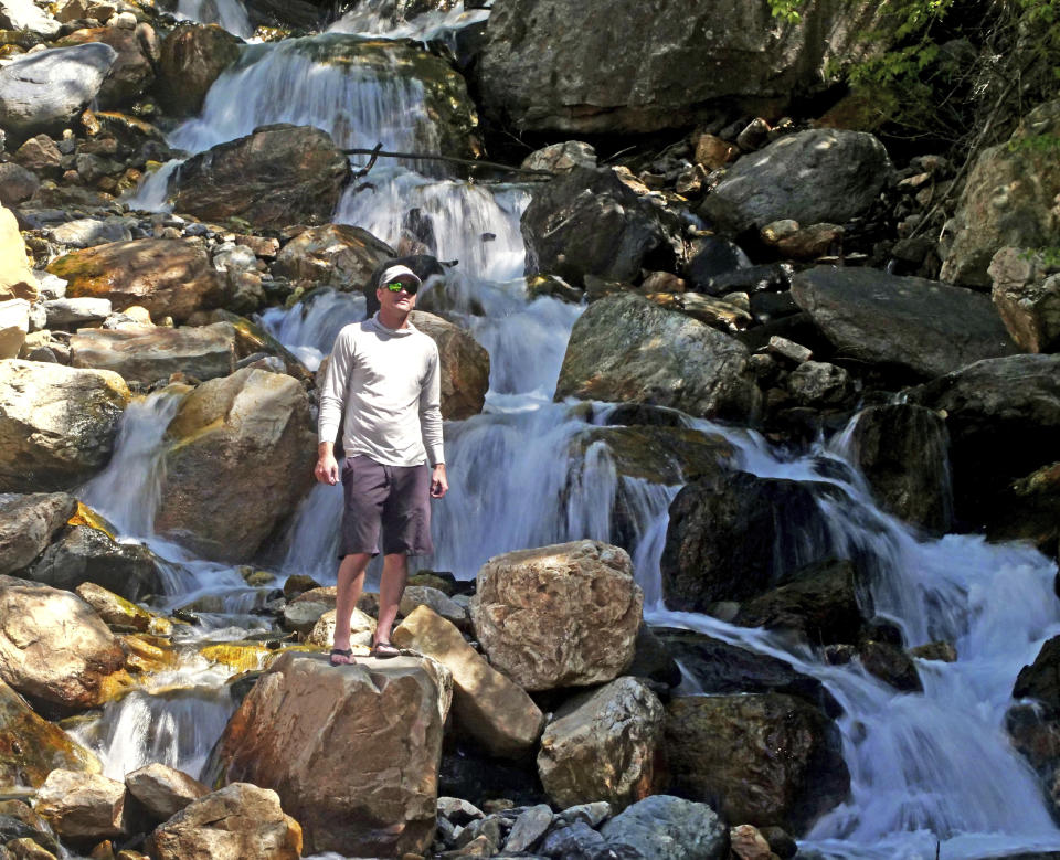 This Monday, June 10, 2019, photo shows hiker Tony Larsen posing for a photograph at a waterfalls, in the Big Cottonwood canyon, near Salt Lake City. The summer's melting snowpack is creating raging rivers that are running high, fast and icy cold. The state's snowpack this winter was about 150 percent higher than the historical average and double the previous year, which was the driest on record dating back to 1874, said Brian McInerney, hydrologist for the National Weather Service in Salt Lake City. (AP Photo/Rick Bowmer)