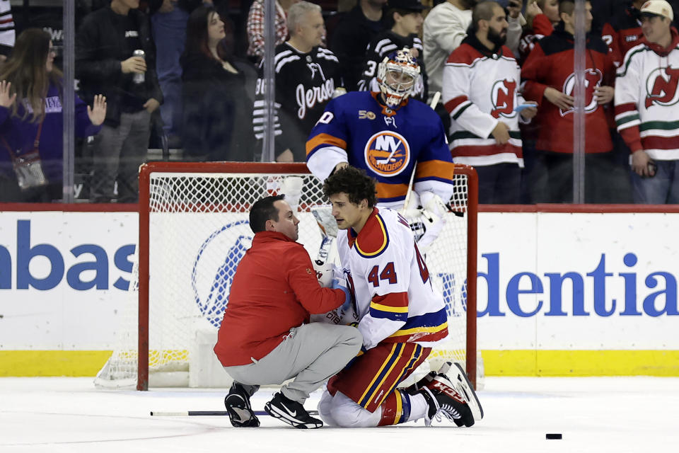 New Jersey Devils left wing Miles Wood is checked on by a team trainer during the second period of an NHL hockey game against the New York Islanders on Friday, Dec. 9, 2022, in Newark, N.J. (AP Photo/Adam Hunger)