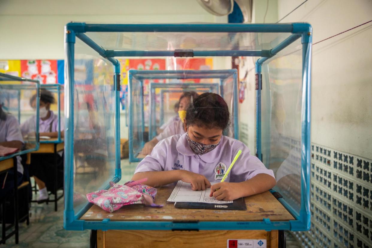 Thai students wear face masks and sit at desks with plastic screens used for social distancing at the Wat Khlong Toey School on August 10, 2020: Getty Images