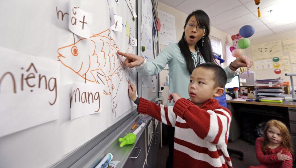 In this photo taken Friday, Feb. 14, 2014, kindergarten teacher Thao Tran helps student Brian Ho learn fish anatomy in Vietnamese in a dual immersion language class at White Center Heights Elementary School in Seattle. In a handful of schools across the country, kindergartners aren’t being taught just in English, but also in Vietnamese. The move to add Vietnamese to the growing list of languages featured in dual immersion education classes comes as the American born children of Vietnamese immigrants are striving to preserve their family’s heritage for the next generation. (AP Photo/Elaine Thompson)