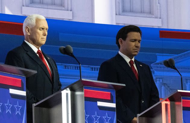 Former Vice President Mike Pence and Florida Gov. Ron DeSantis close their eyes during the first Republican presidential primary debate, Aug. 23, in Milwaukee.