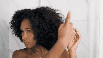 woman spraying product on her curly hair