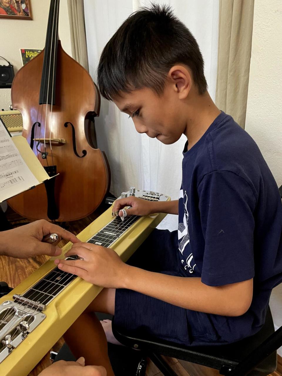 A boy learns steel guitar.