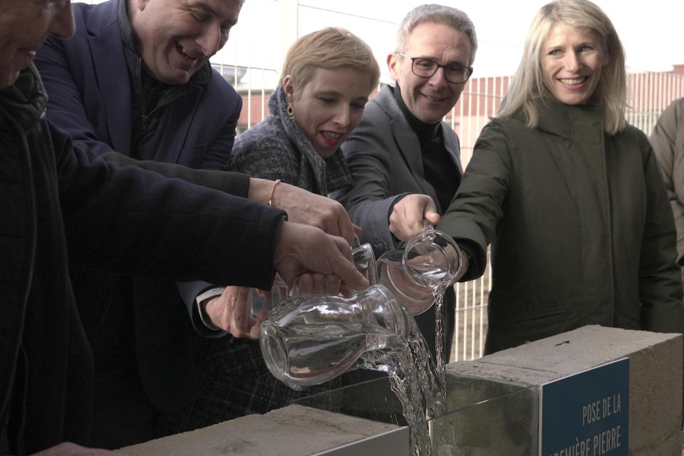 Stephane Blanchet, mayor of the Paris-region town of Sevran,second from left, and other officials pour jugs of water at a Jan. 24, 2024, ceremony to celebrate the start of building works to accommodate a new swimming pool in Sevran. The town of 51,000 people in the Seine-Saint-Denis region north of Paris is inheriting one of the pools that will be used for the Olympic and Paralympic Games in Paris this summer. (AP Photo/John Leicester)