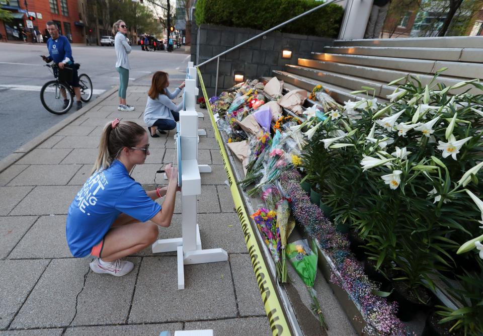 Kelly Morris, left, and her mom Cathy Morris leave inspirational messages on a makeshift memorial placed in front of the Old National Bank to honor the victims of the mass shooting that occurred earlier in the week in Louisville, Ky. on Apr. 11, 2023.  