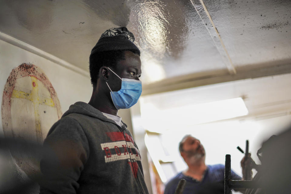 Waly Sarr, 30, from Senegal, works on the deck of the "Vincenzo Padre" fishing boat where he works as fisherman, in the Island of Lampedusa, southern Italy, Thursday, May 13, 2021. The tiny island of Lampedusa, which is closer to Africa than the Italian mainland, is in the throes of yet another season of migrant arrivals, and Sarr and his fellow countryman Ibrahima Mbaye can only watch from shore as their fellow African countrymen risk their lives to get here via smugglers' boats. (AP Photo/Salvatore Cavalli)