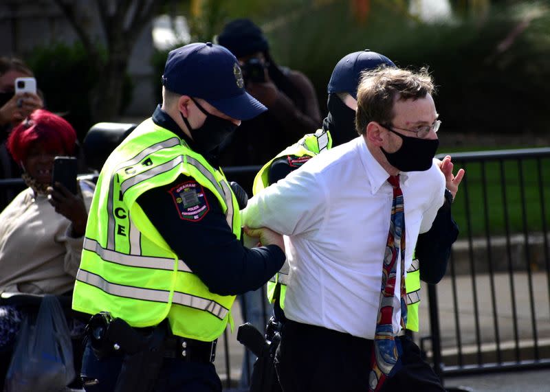 A man is detained by Graham Police officers after a moment of silence during a Get Out The Vote march in Graham