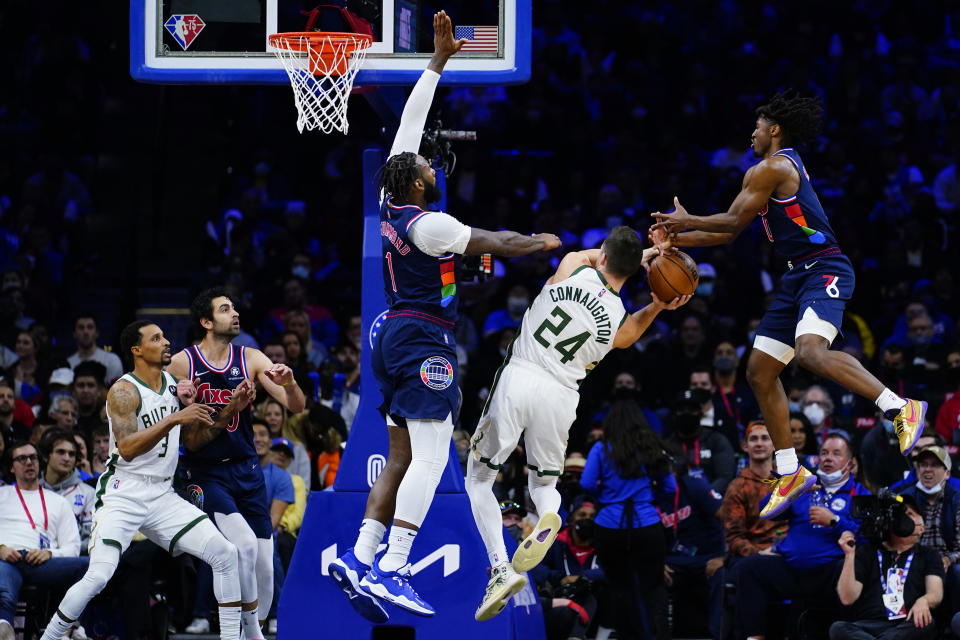 Milwaukee Bucks' Pat Connaughton (24) cannot get a shot past Philadelphia 76ers' Tyrese Maxey (0) and Andre Drummond (1) during the second half of an NBA basketball game, Tuesday, Nov. 9, 2021, in Philadelphia. (AP Photo/Matt Slocum)