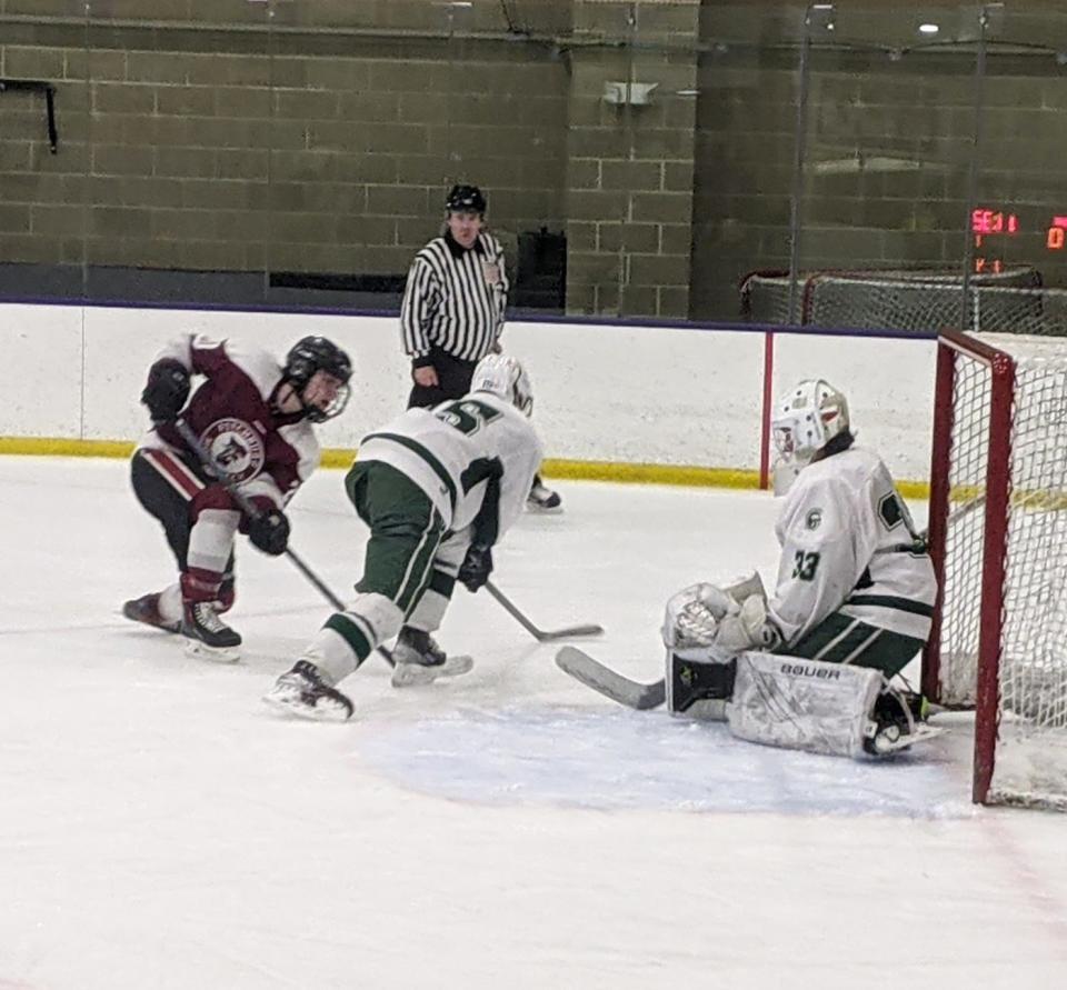 Fitchburg/Monty Tech's Colin Hines, left, fires a shot on goal against Oakmont goaltender Cathal Wells (33) and defenseman Jack Carney (15) during Wednesday's game at Iorio Arena in Ashburnham.